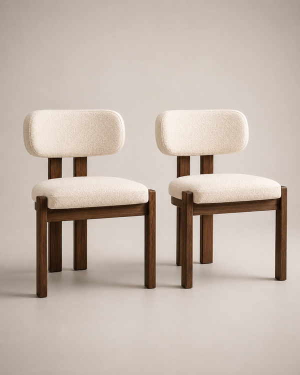 Two modern dining chairs with cream bouclé upholstered seats and rounded backs, supported by dark brown wooden frames, shown against a neutral beige studio background.
