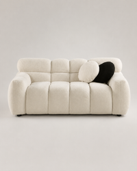 Aurelia Bouclé Sofa in warm ivory bouclé upholstery with a curved modern silhouette on a premium light grey studio background.