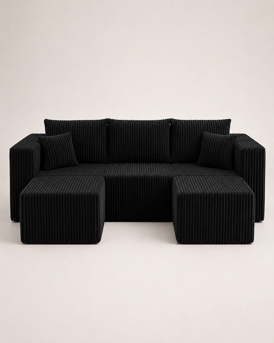 A modern black corduroy sectional sofa with two matching square ottomans, photographed against a clean, light off-white studio background.