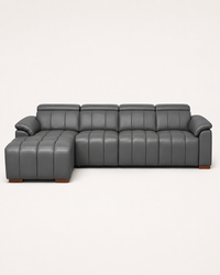 A modern gray leather sectional sofa with a left-facing chaise ottoman and vertical channel tufting, shown against a plain off-white background.