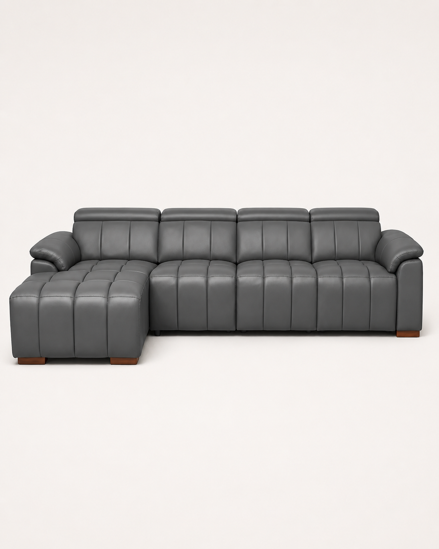 A modern gray leather sectional sofa with a left-facing chaise ottoman and vertical channel tufting, shown against a plain off-white background.