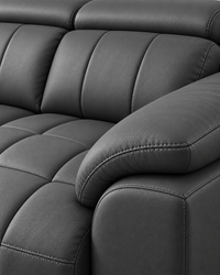 Close-up of a dark gray leather reclining sofa with tufted seat cushions, a padded armrest, and visible stitching.