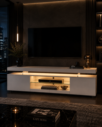 A modern white media console with integrated warm under-shelf lighting, styled in a contemporary dark living room setting with a large black TV on the wall.