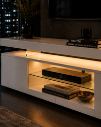 A modern white floating TV stand with integrated warm LED lighting and a glass shelf, styled in a contemporary living room setting.
