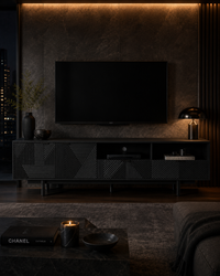A modern black TV stand with geometric carved details, supporting a large black flat-screen TV in a dark, stylishly lit living room.