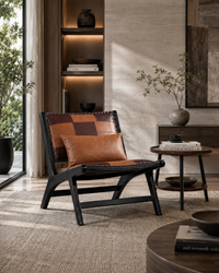 A modern lounge chair with a black wooden frame and brown leather patchwork upholstery, styled in a warm, contemporary living room setting.