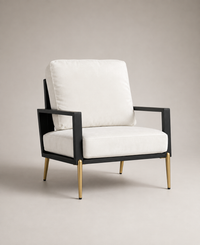A modern accent chair featuring white plush cushions, a black metal frame, and slim gold-finished legs, photographed against a neutral beige studio background.
