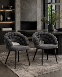 Two modern tufted dining chairs in dark gray velvet with black legs, styled in a contemporary dining room setting.