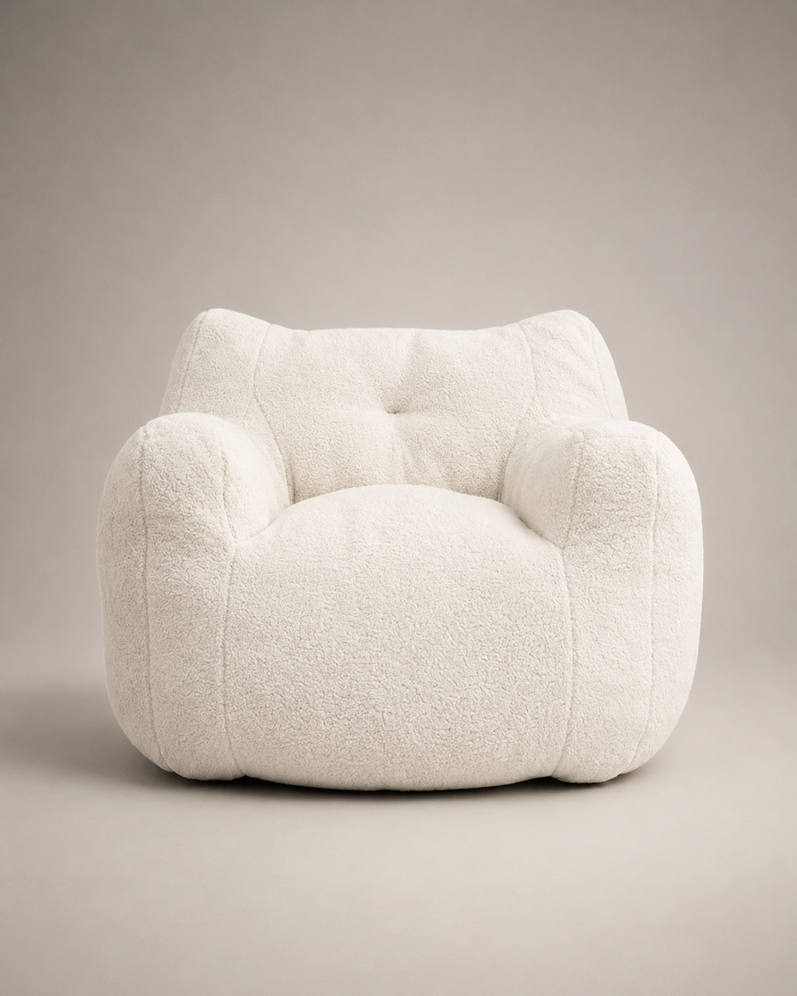 A plush, rounded armchair upholstered in a textured bouclé fabric, shown from the front against a neutral warm gray studio background.