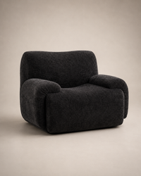 A dark charcoal gray upholstered armchair with a rounded, modern silhouette, shown against a neutral beige studio background.
