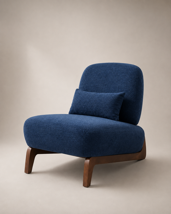 A modern accent chair with deep blue textured upholstery and curved wooden legs, featuring a matching blue lumbar pillow, set against a neutral beige studio background.