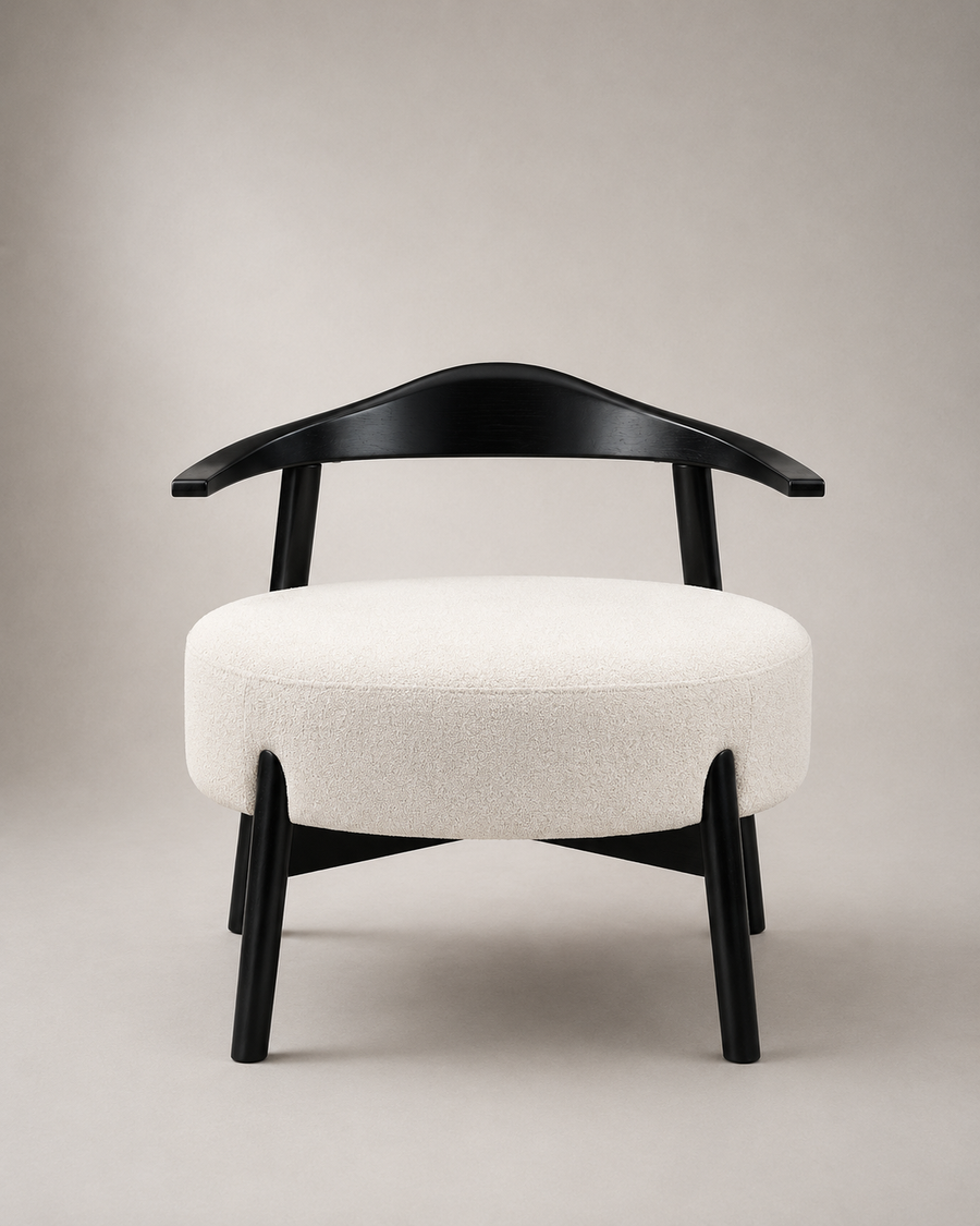 A modern accent chair with a curved black wooden frame and a round, plush off-white upholstered seat, shown against a neutral beige studio background.