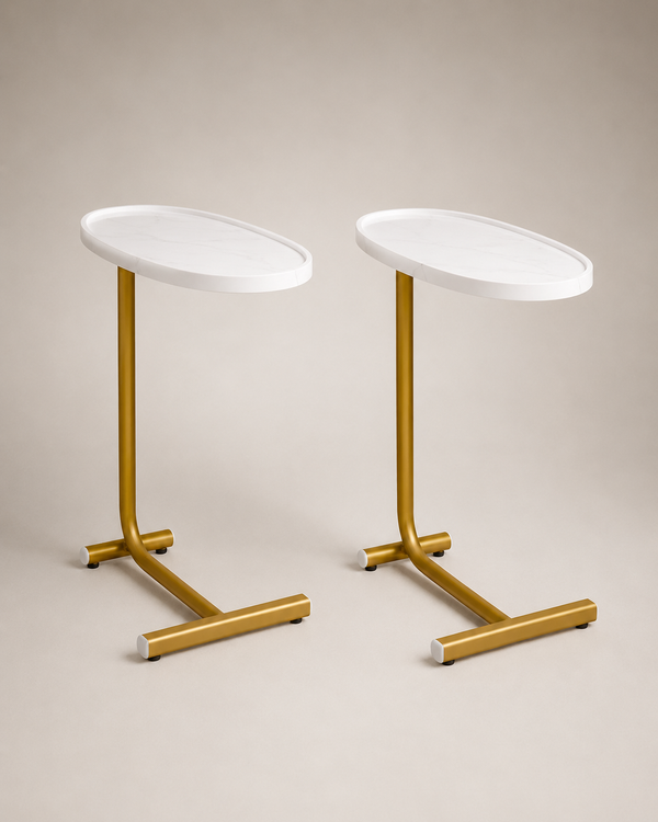 Two modern side tables with oval white tops and gold metal pedestal bases, shown on a neutral beige studio background.