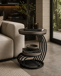 A modern round nesting side table with a dark wood top and black curved metal frame, styled next to a beige sofa in a contemporary living room.