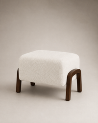 A modern square ottoman with a textured off-white bouclé upholstered top and curved dark brown wooden legs, shown on a neutral beige studio background.