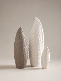 Three textured ceramic vases in varying heights, featuring a hammered leaf-like pattern, displayed on a neutral beige surface against a soft beige background.