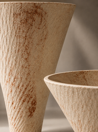 Two textured ceramic vases in a warm beige and brown earthy finish, shown in a close-up studio shot with soft shadows.