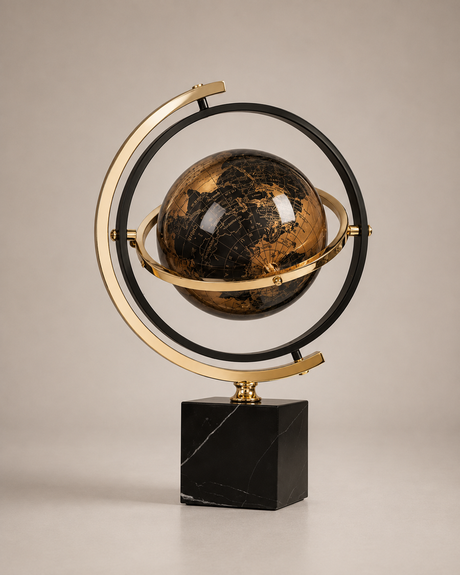 A decorative globe sculpture with a black and gold marbled sphere, surrounded by a gold and black ring frame, mounted on a polished black marble base against a neutral beige background.