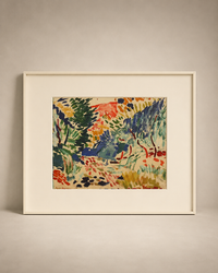 A framed art print featuring an impressionist landscape painting with green trees, red foliage, and blue accents, set in a cream-colored frame against a neutral beige wall.