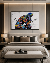 A large framed wall art print depicting a colorful, paint-splattered muscular figure in a crouched pose, displayed above a neatly made bed in a modern bedroom setting.