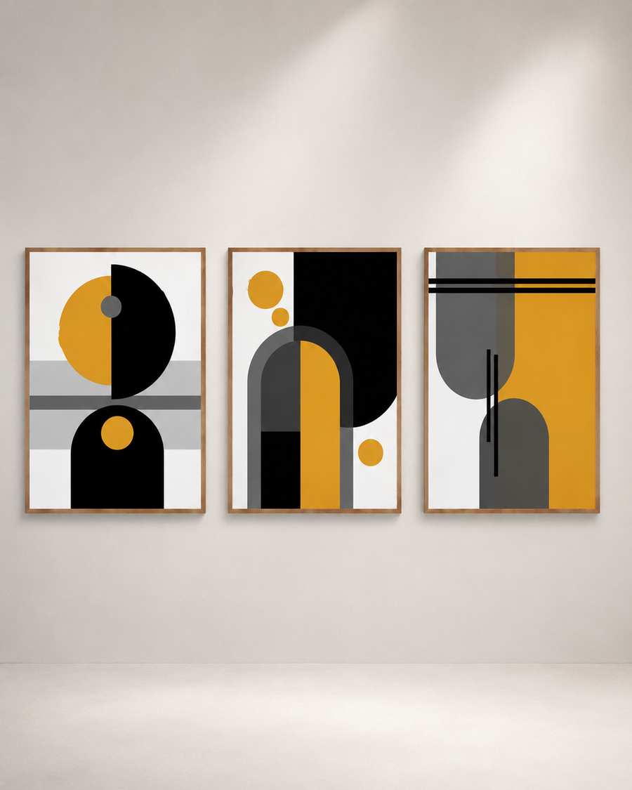 Three framed abstract geometric wall art prints hang side by side on a light gray wall. The artwork features bold shapes in black, mustard yellow, gray, and white, enclosed in thin light wood frames.
