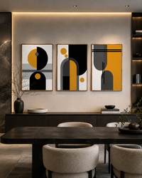 Three framed abstract geometric wall art prints in black, white, gray, and mustard yellow hang above a dark wood console in a modern dining room with upholstered chairs.
