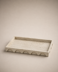 Aurevia rectangular travertine-inspired decorative tray with sculpted arch detailing on warm greige studio background