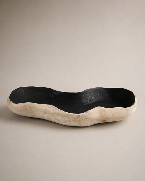 A rustic, organic-shaped wooden bowl with a black lacquered interior and a natural light beige wood exterior, photographed on a neutral beige background.