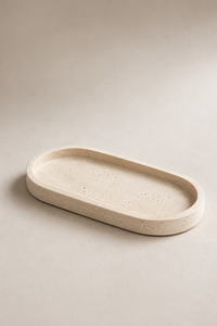 An oval concrete tray with a textured, speckled beige surface, photographed on a matching neutral beige background.