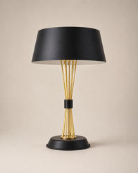 A modern table lamp with a matte black conical shade, a gold-finished wire stem structure, and a black circular base, set against a solid beige background.