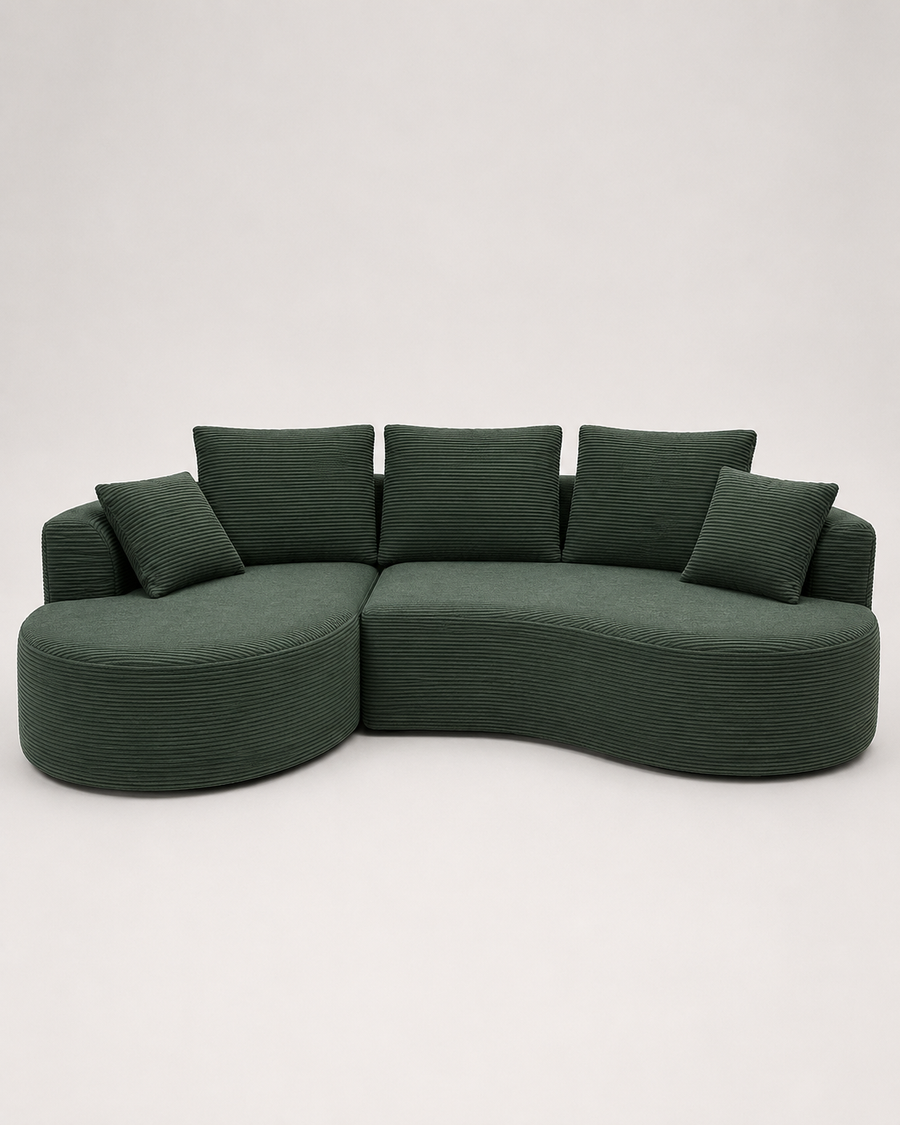 A curved modular upholstered sofa in dark green corduroy fabric with matching square throw pillows, photographed against a plain light gray studio background.