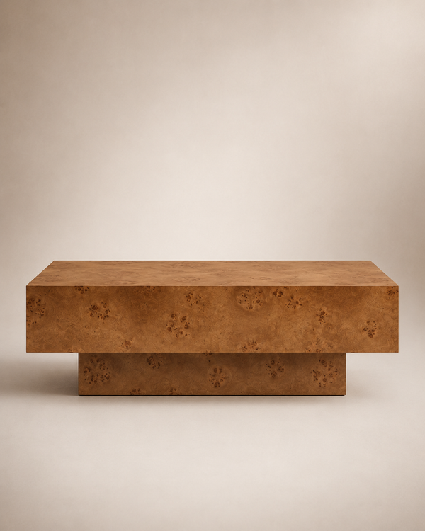 A modern low coffee table with a thick rectangular top and a tiered base, both featuring a rich, textured burl wood grain in warm brown and golden tones, set against a neutral beige background.