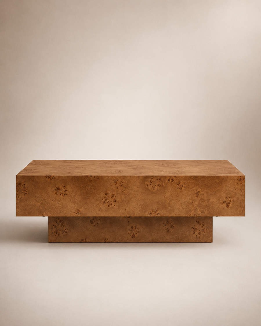 A modern low coffee table with a thick rectangular top and a tiered base, both featuring a rich, textured burl wood grain in warm brown and golden tones, set against a neutral beige background.