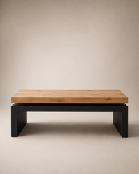A modern low coffee table with a light natural wood top and a matte black metal base, photographed against a neutral beige studio background.