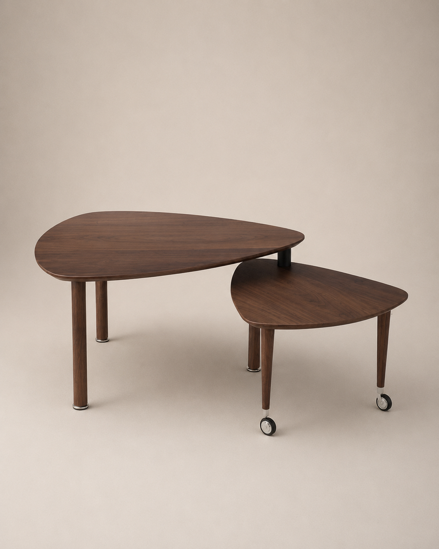 Two nested triangular wooden nesting tables with tapered legs, one larger and one smaller, both on casters, photographed against a solid beige studio background.