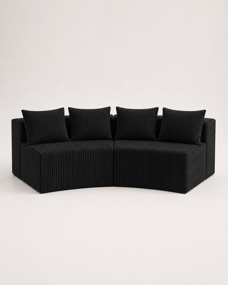 A curved outdoor sectional sofa upholstered in black corduroy fabric with four matching square back cushions, shown against a plain light gray studio background.