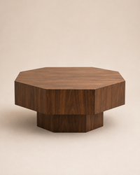 A modern octagonal wooden coffee table with a dark walnut finish, featuring a tiered design with a thick top and a solid pedestal base, set against a warm beige background.