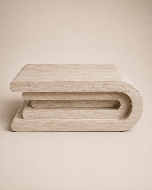 A modern sculptural coffee table made of light beige travertine stone, featuring a curved top and layered geometric design, set against a solid beige background.